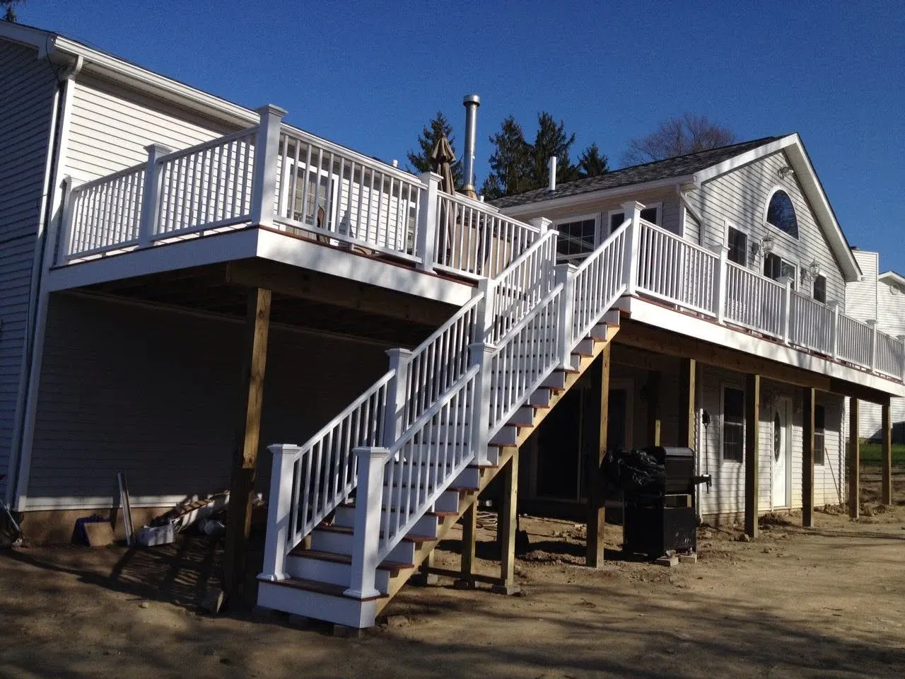 White deck and staircase attached to residential house under clear blue sky