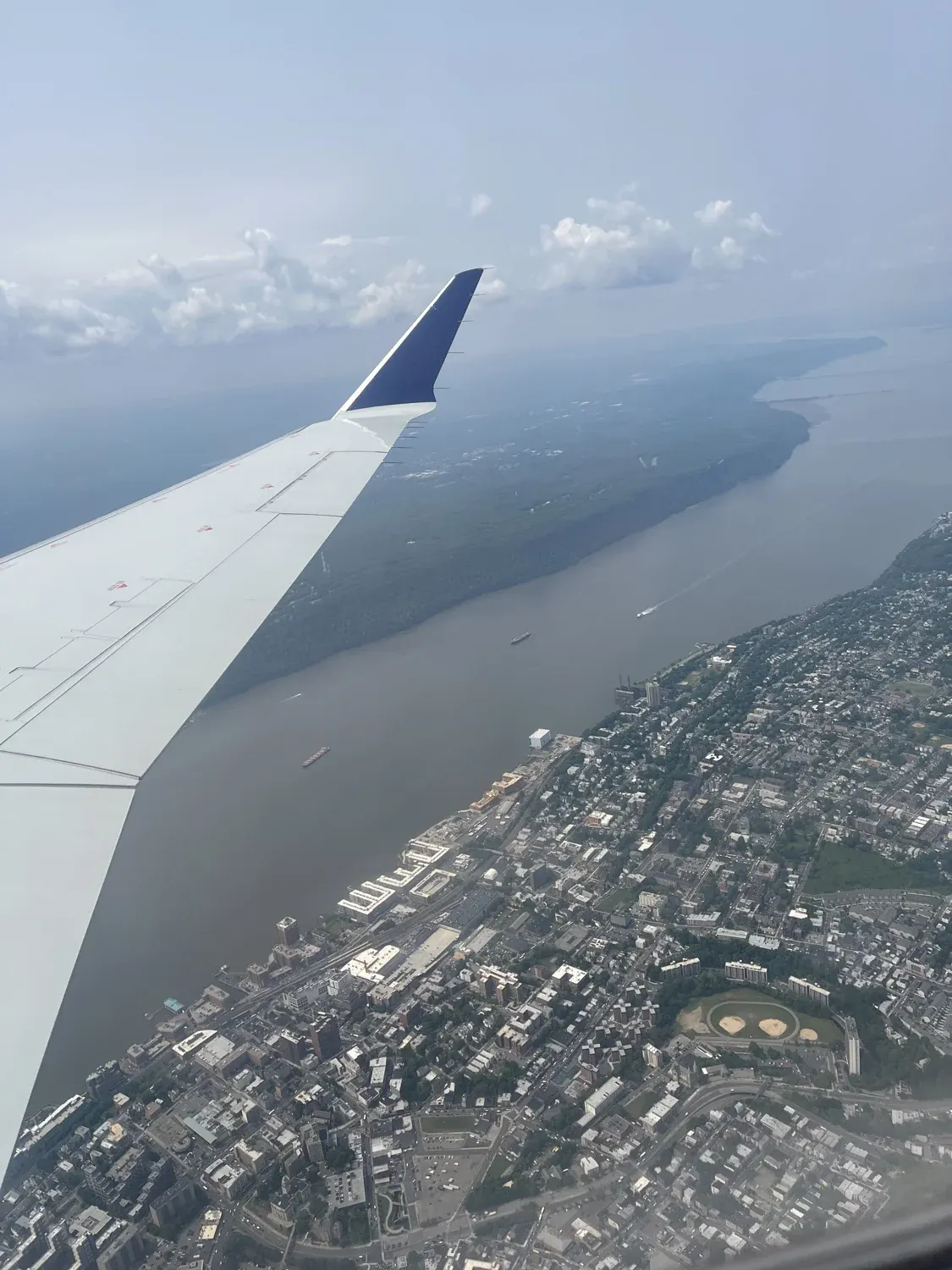 Airplane wing over river and city during flight