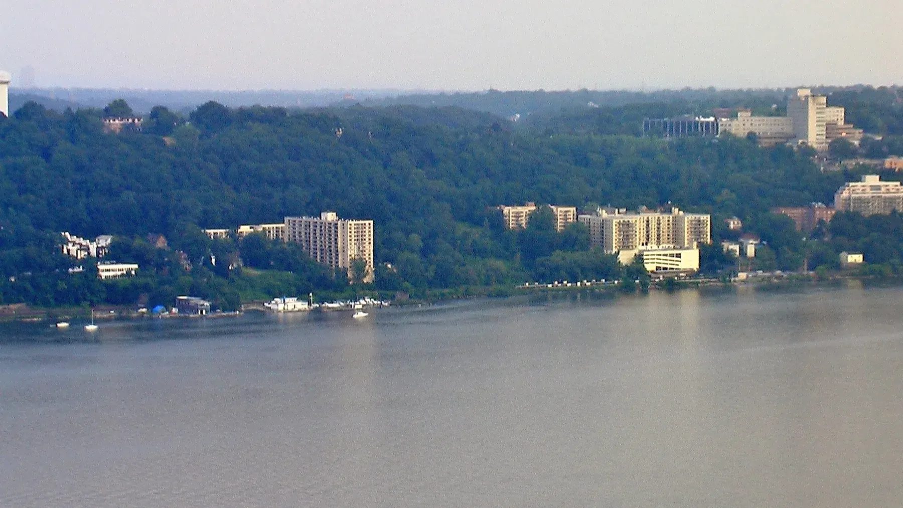 Riverside residential buildings and forest landscape along waterway at dawn